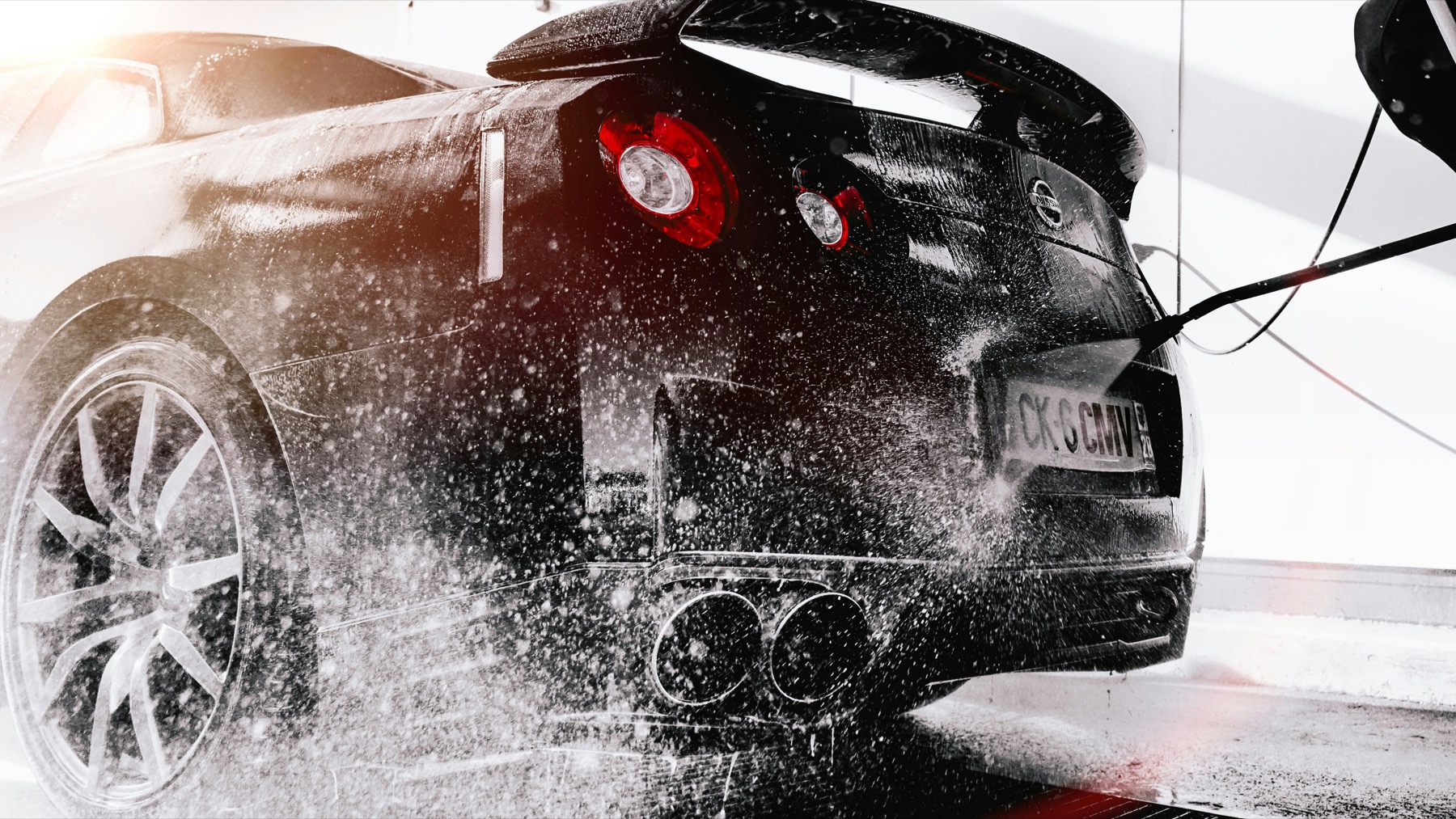 A black sports car being carefully pressure washed