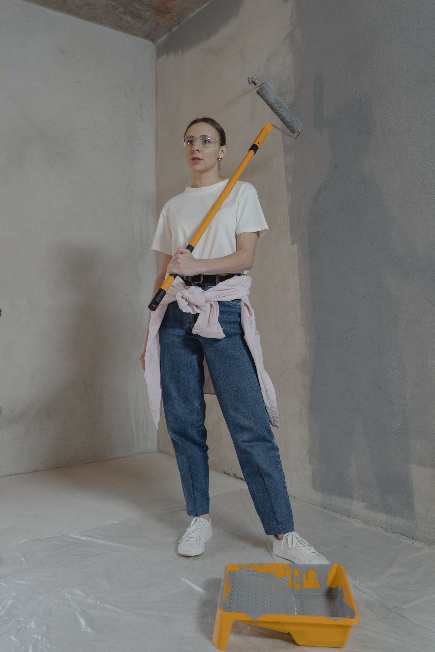 A person holding a paint roller in a room being renovated